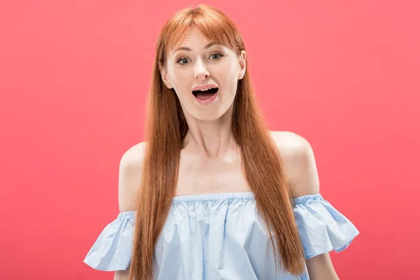 Vue de face de femme rousse choquée regardant la caméra avec la bouche ouverte isolé sur rose — Photo de stock