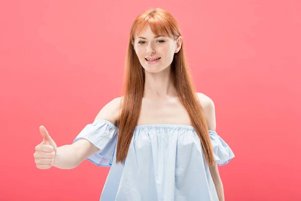 Confident redhead girl smiling and showing thumb up isolated on pink — Stock Photo