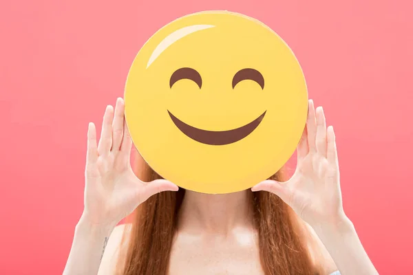 KYIV, UKRAINE - MAY 23, 2019: front view of redhead girl holding smiley isolated on pink — Stock Photo