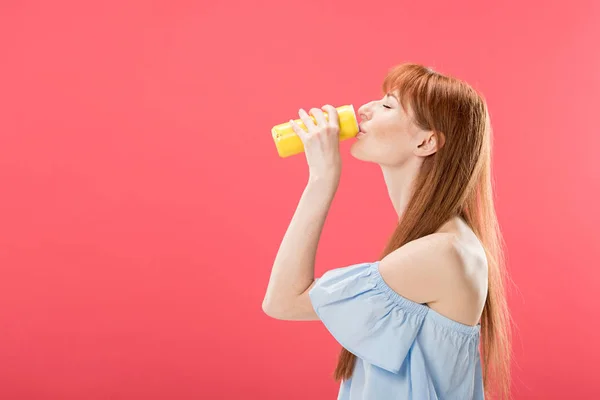 Vue latérale de rousse fille boisson à boire isolé sur rose — Photo de stock