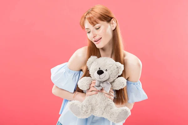 Lächelnde rothaarige junge Frau hält Teddybär isoliert auf rosa — Stockfoto
