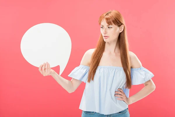 Missbilligte attraktive rothaarige Mädchen mit der Hand auf der Hüfte stehen und halten leere Sprechblase isoliert auf rosa — Stockfoto