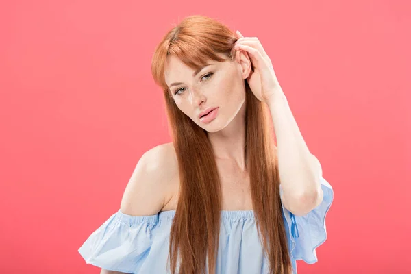 Sensual redhead girl touching hair and looking at camera isolated on pink — Stock Photo