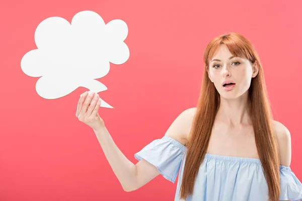 Sorprendido pelirroja joven sosteniendo vacío pensamiento burbuja aislado en rosa - foto de stock