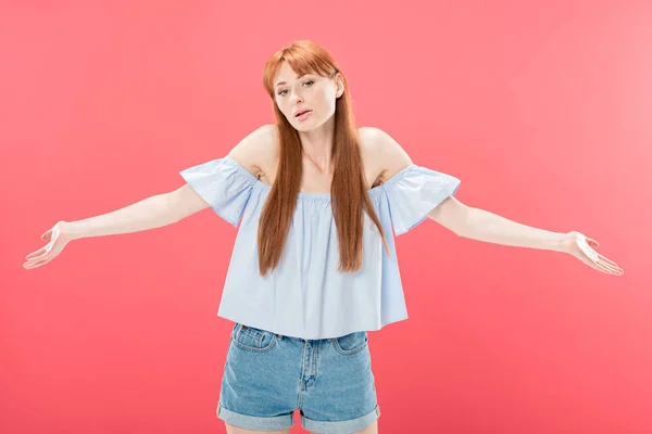 Redhead young woman looking at camera and showing shrug gesture isolated on pink — Stock Photo