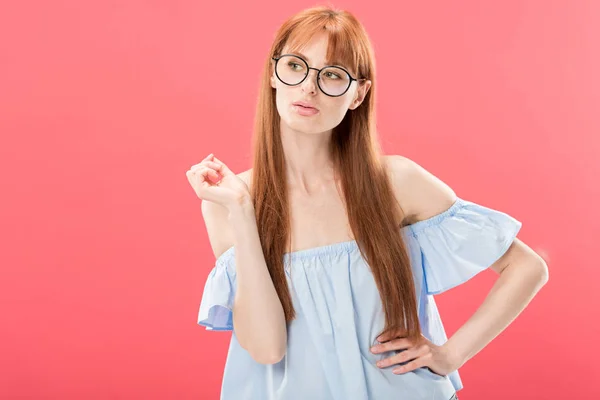 Pensive redhead girl in glasses looking away isolated on pink — Stock Photo