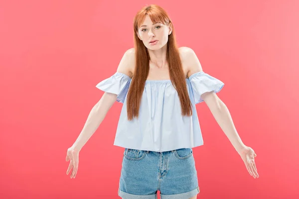 Redhead young woman looking at camera and showing shrug gesture isolated on pink — Stock Photo