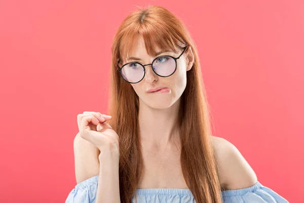 Pensativo pelirroja chica en gafas mirando lejos aislado en rosa - foto de stock