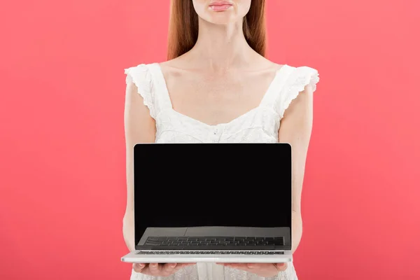 Vue recadrée de rousse jeune femme dans des lunettes tenant ordinateur portable avec écran blanc isolé sur rose — Photo de stock