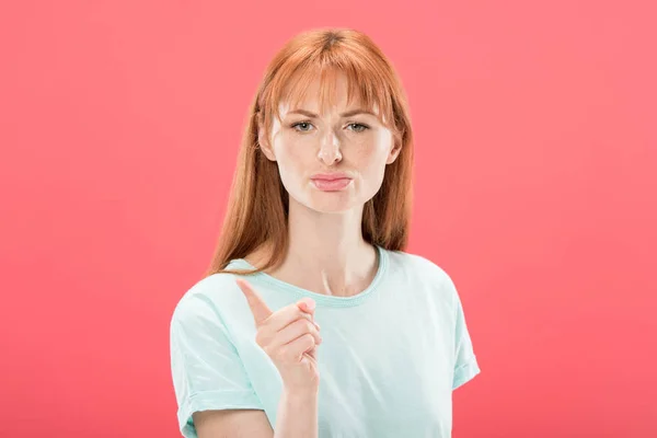 Vista frontal de chica pelirroja disgustada en camiseta mirando a la cámara y sacudiendo el dedo aislado en rosa - foto de stock