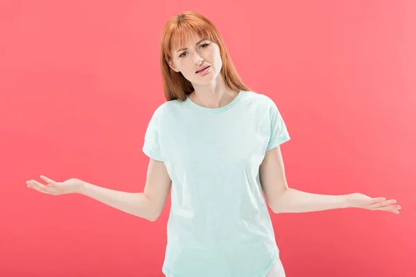 Vista frontal de mulher ruiva descontente em t-shirt olhando para a câmera e fazendo gesto encolher de ombros isolado em rosa — Fotografia de Stock