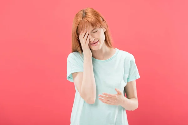 Front view of young redhead woman in t-shirt with headache touching head isolated on pink — Stock Photo