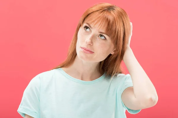 Pensive redhead young woman looking away and touching hair isolated on pink — Stock Photo