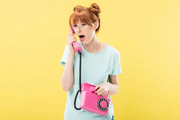 Chocado ruiva jovem mulher falando no retro telefone isolado no amarelo — Fotografia de Stock