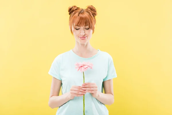 Vista frontale sorridente rossa giovane donna in t-shirt con fiore isolato su giallo — Foto stock