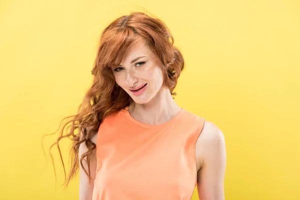 Smiling curly redhead woman looking at camera isolated on yellow — Stock Photo