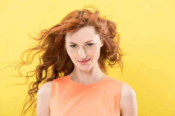 Vue de face de sourire rousse bouclée femme regardant caméra isolée sur jaune — Photo de stock