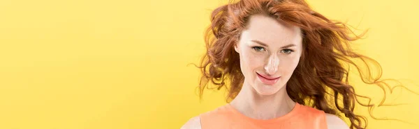 Panoramic shot of smiling curly redhead woman looking at camera isolated on yellow — Stock Photo