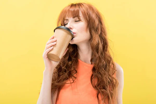 Curly redhead girl drinking coffee with closed eyes isolated on yellow — Stock Photo