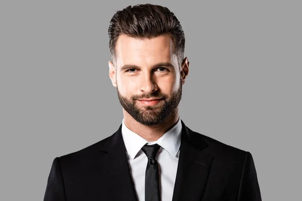 Sonriente hombre de negocios guapo en traje negro aislado en gris - foto de stock