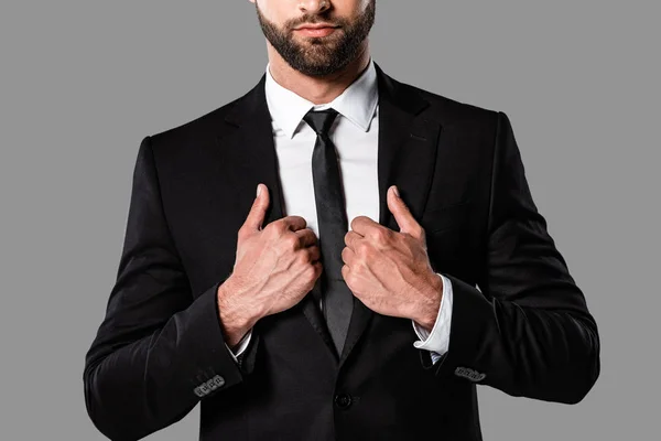 Vista recortada de elegante hombre de negocios barbudo en traje negro aislado en gris - foto de stock