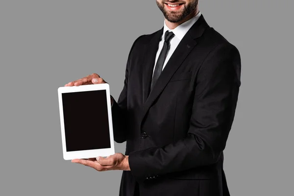 Vista recortada de empresário sorridente em terno preto mostrando tablet digital com tela em branco isolado em cinza — Fotografia de Stock