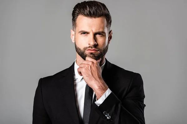 Hombre de negocios guapo pensativo en traje negro aislado en gris - foto de stock