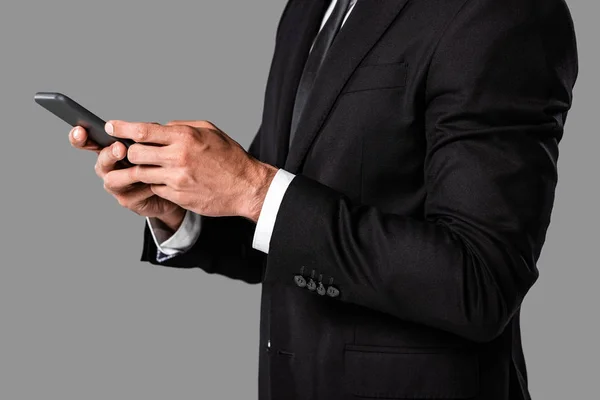 Teilbild des Geschäftsmannes im schwarzen Anzug mit Smartphone isoliert auf grau — Stockfoto