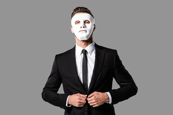 Confiado hombre de negocios guapo en traje negro y máscara blanca aislado en gris - foto de stock