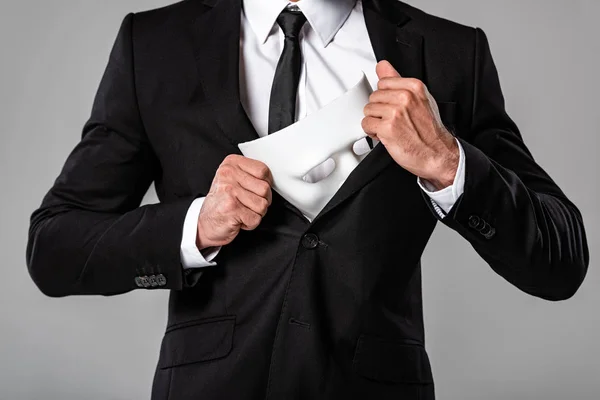 Vista ritagliata di uomo d'affari in tuta nera con maschera bianca isolata su grigio — Foto stock