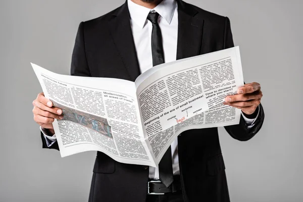 Teilansicht des Geschäftsmannes im schwarzen Anzug mit Zeitung auf Grau — Stockfoto