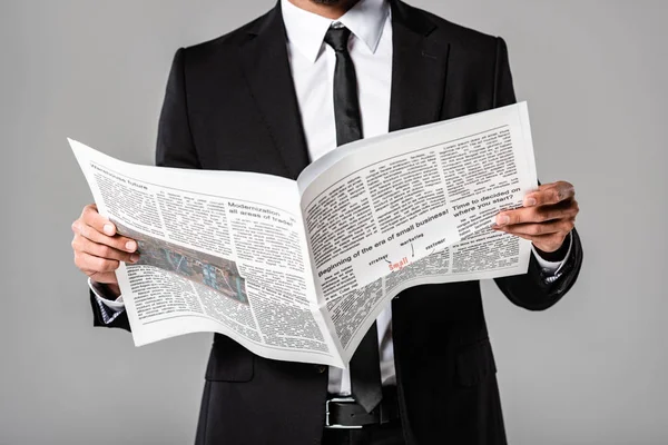 Vue partielle de l'homme d'affaires en costume noir avec journal isolé sur gris — Photo de stock