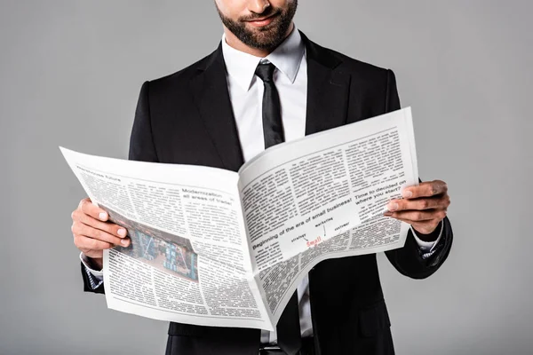 Vista ritagliata di uomo d'affari in abito nero con giornale isolato su grigio — Foto stock