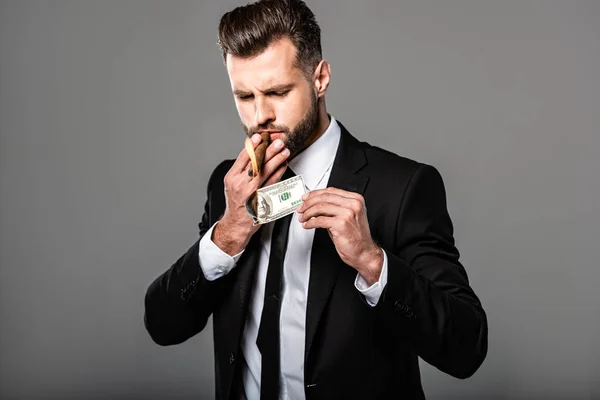 Богатый бизнесмен, закуривающий сигару из горящей долларовой купюры, изолированной на сером — стоковое фото