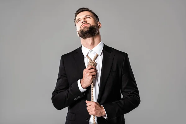 Homme d'affaires déprimé en costume noir nouer noeud sur le cou isolé sur gris — Photo de stock