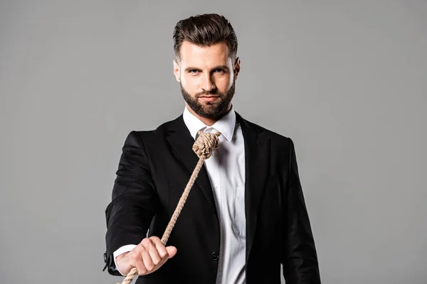 Depressed businessman in black suit with noose on neck holding rope isolated on grey — Stock Photo