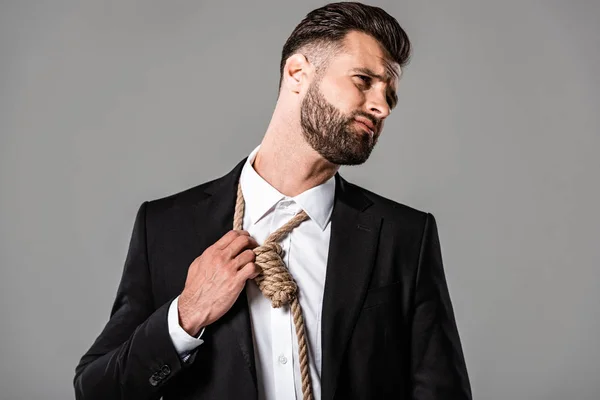 Depressed businessman in black suit touching noose on neck isolated on grey — Stock Photo