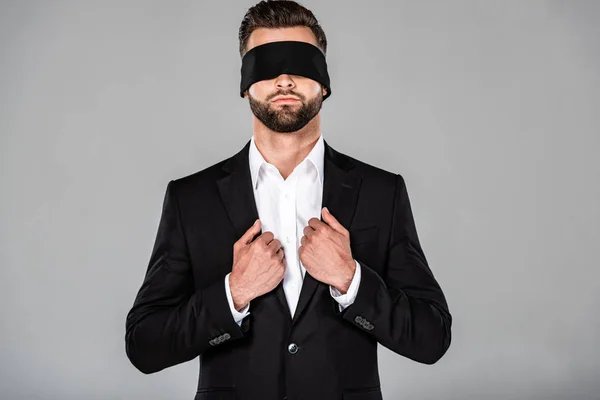 Stylish handsome blindfolded businessman in black suit isolated on grey — Stock Photo