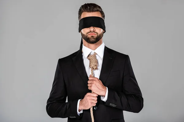 Homme d'affaires les yeux bandés en costume noir tenant noeud isolé sur gris — Photo de stock