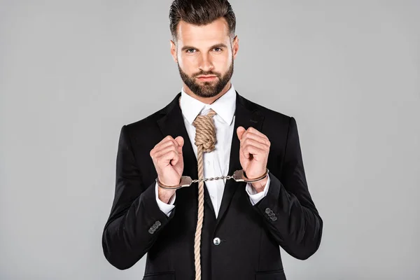 Geschäftsmann im schwarzen Anzug und Handschellen mit Schlinge am Hals isoliert auf grau — Stockfoto