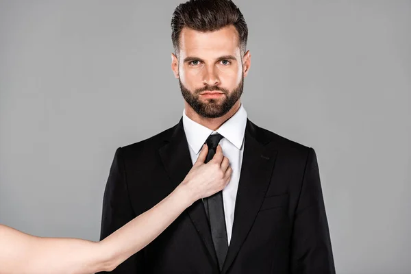 Mujer atando corbata en hombre de negocios en traje negro aislado en gris - foto de stock