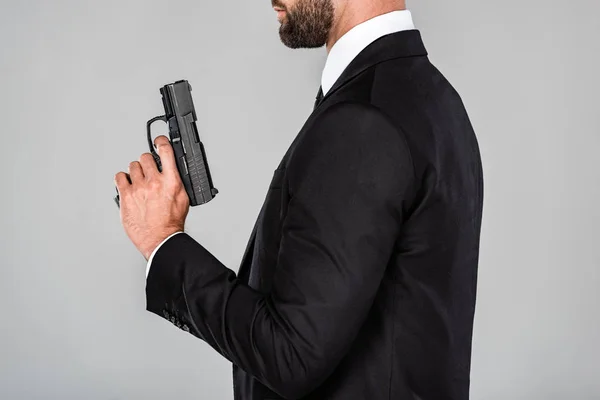 Vista ritagliata dell'agente in completo nero con pistola isolata su grigio — Foto stock