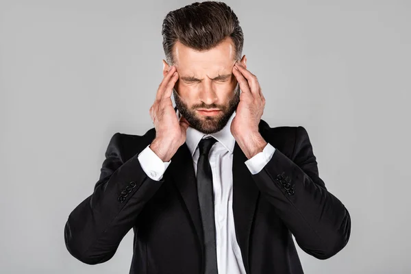 Hombre de negocios agotado en traje negro con dolor de cabeza aislado en gris - foto de stock