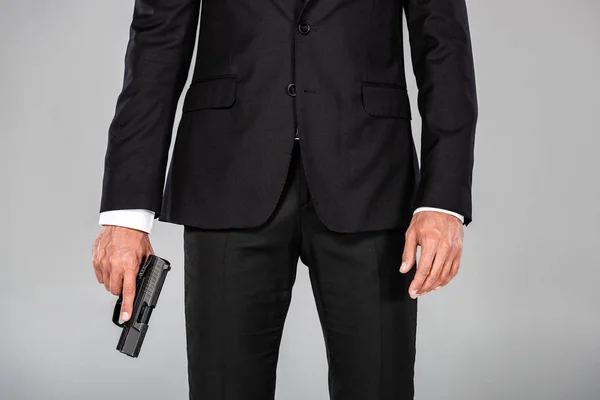 Partial view of agent in black suit with gun isolated on grey — Stock Photo