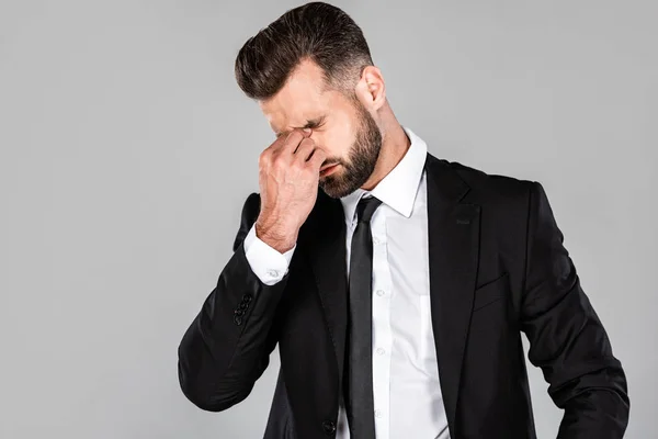 Втомлений успішний бізнесмен в чорному костюмі потирає очі ізольовано на сірому — стокове фото