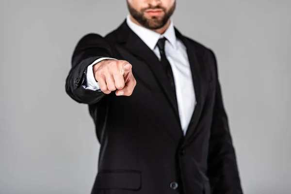 Recortado vista de hombre de negocios en traje negro apuntando con el dedo a la cámara aislado en gris — Stock Photo