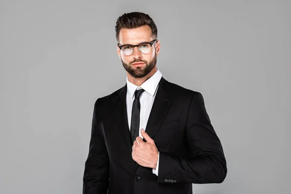 Sério empresário bem sucedido em terno preto e óculos isolados em cinza — Fotografia de Stock