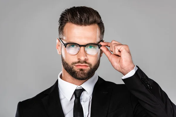 Успешный бизнесмен в черном костюме и в очках, изолированных на сером — стоковое фото