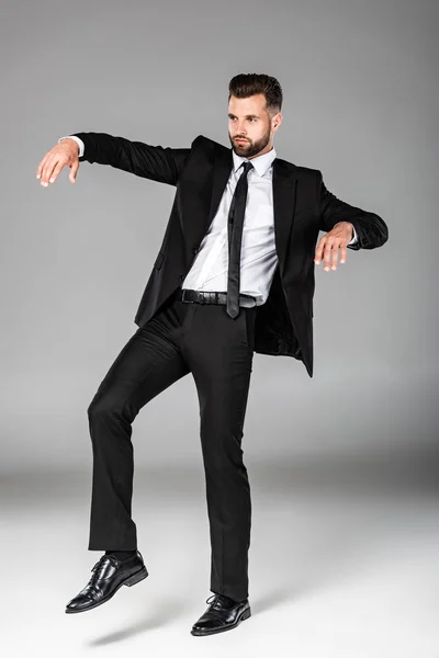 Vista completa del hombre de negocios zombi en traje negro en gris - foto de stock