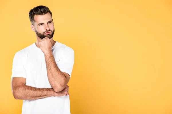 Thoughtful handsome man in white t-shirt isolated on yellow with copy space — Stock Photo